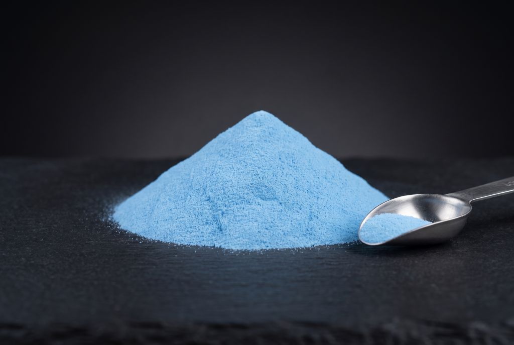 Photoluminescent pigment, blue, as a heap with a scoop, in daylight