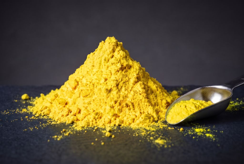 Nachleuchtpigment Gelb-Neongelb als Häufchen mit Messlöffel bei Tageslicht
