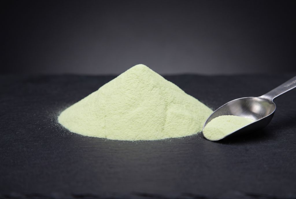 Photoluminescent pigment, yellow-green, as a heap with a scoop, in daylight