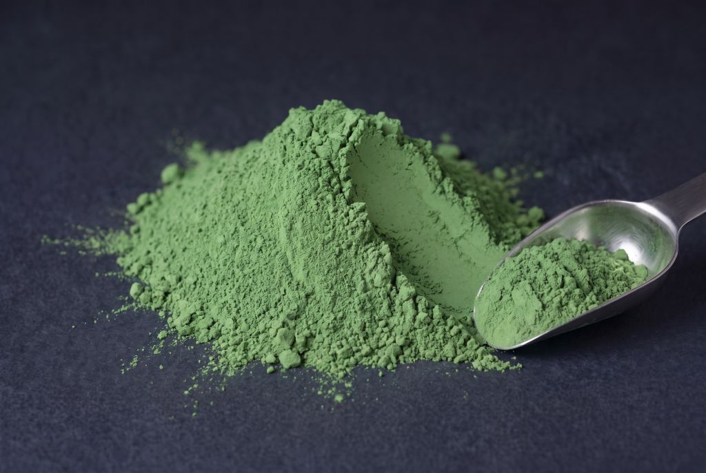 Nachleuchtpigment Grün-Grün als Häufchen mit Messlöffel bei Tageslicht