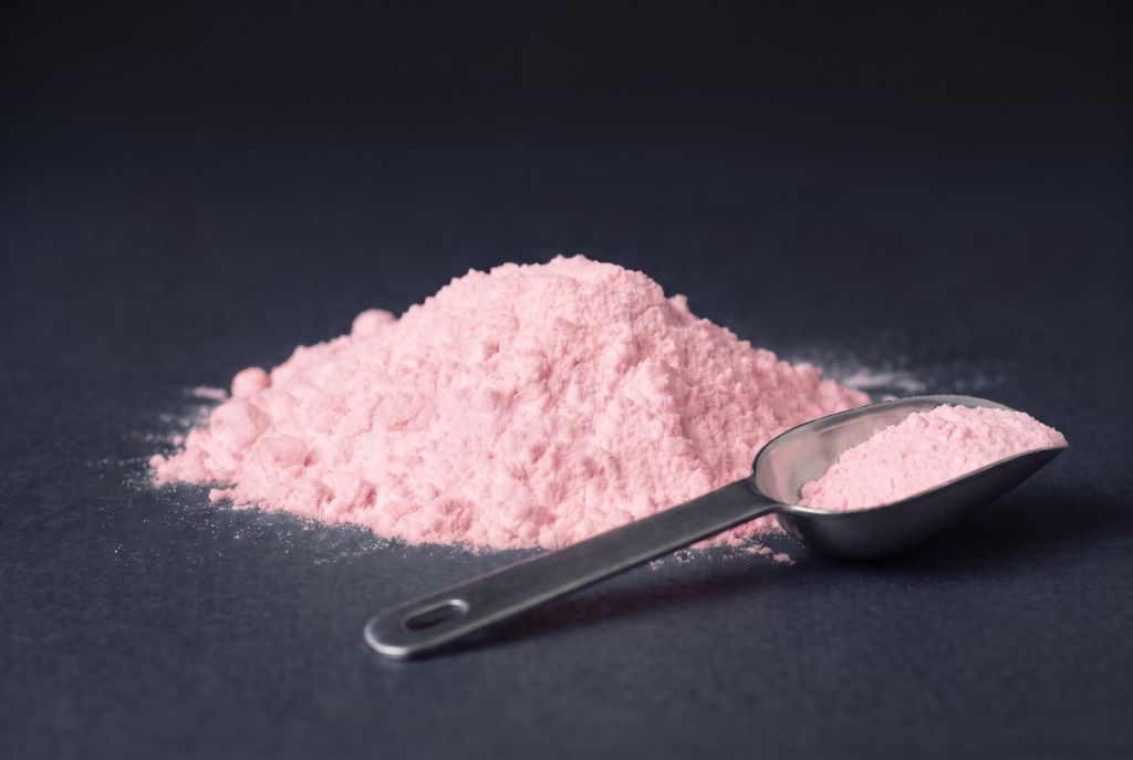 Nachleuchtpigment Pink-Lila als Häufchen mit Messlöffel bei Tageslicht