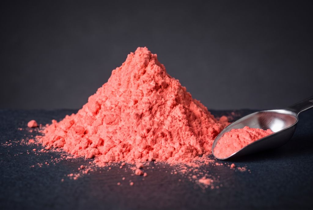Nachleuchtpigment Rot als Häufchen mit Messlöffel bei Tageslicht